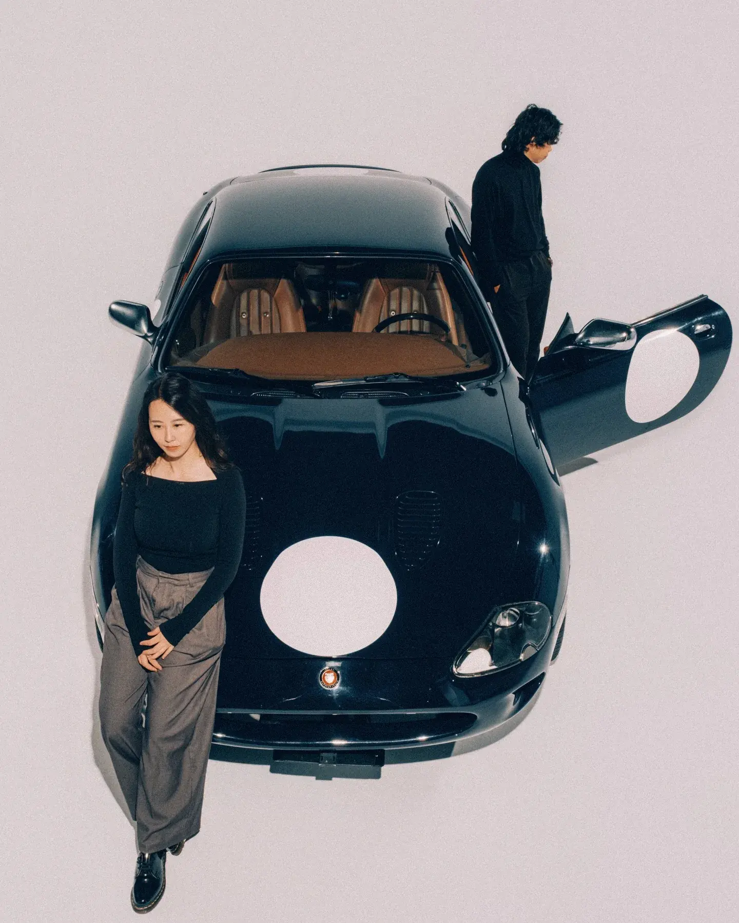Dark classic coupe photographed in a studio setting with two people